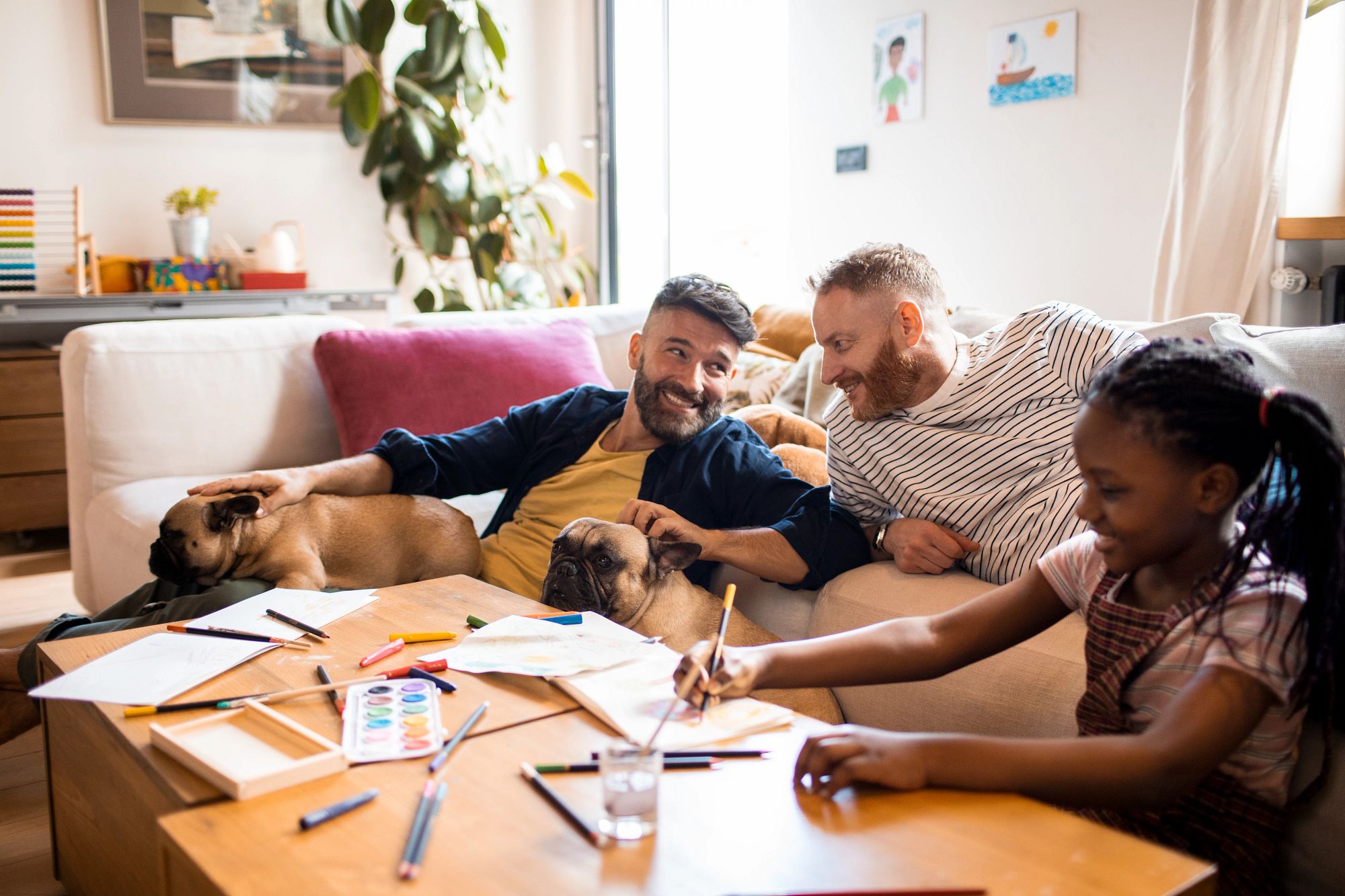 family sitting around coffee table, smiling and doing crafts
